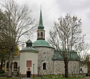 Gammal kyrka byggd med stenblock. Koppartaket är vackert ärgat